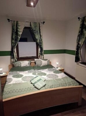 Ein Schlafzimmer mit Bett, Vorhängen, einem Fenster und Nachttischlampen.