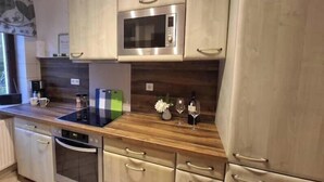 A modern kitchen with stainless steel appliances, wooden countertops, and light-colored cabinetry. - Ulbersdorf Mill "Försterstübchen" (Hohnstein)