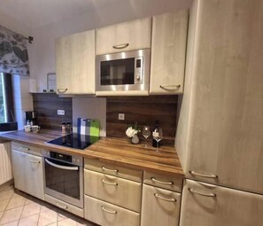Eine moderne Küche mit Edelstahlgeräten, Holz Arbeitsplatten und hellen Schränken.