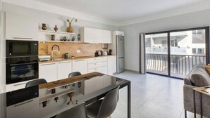 Een moderne keuken met witte kastjes, een houten aanrecht en een eethoek met een glazen tafel.