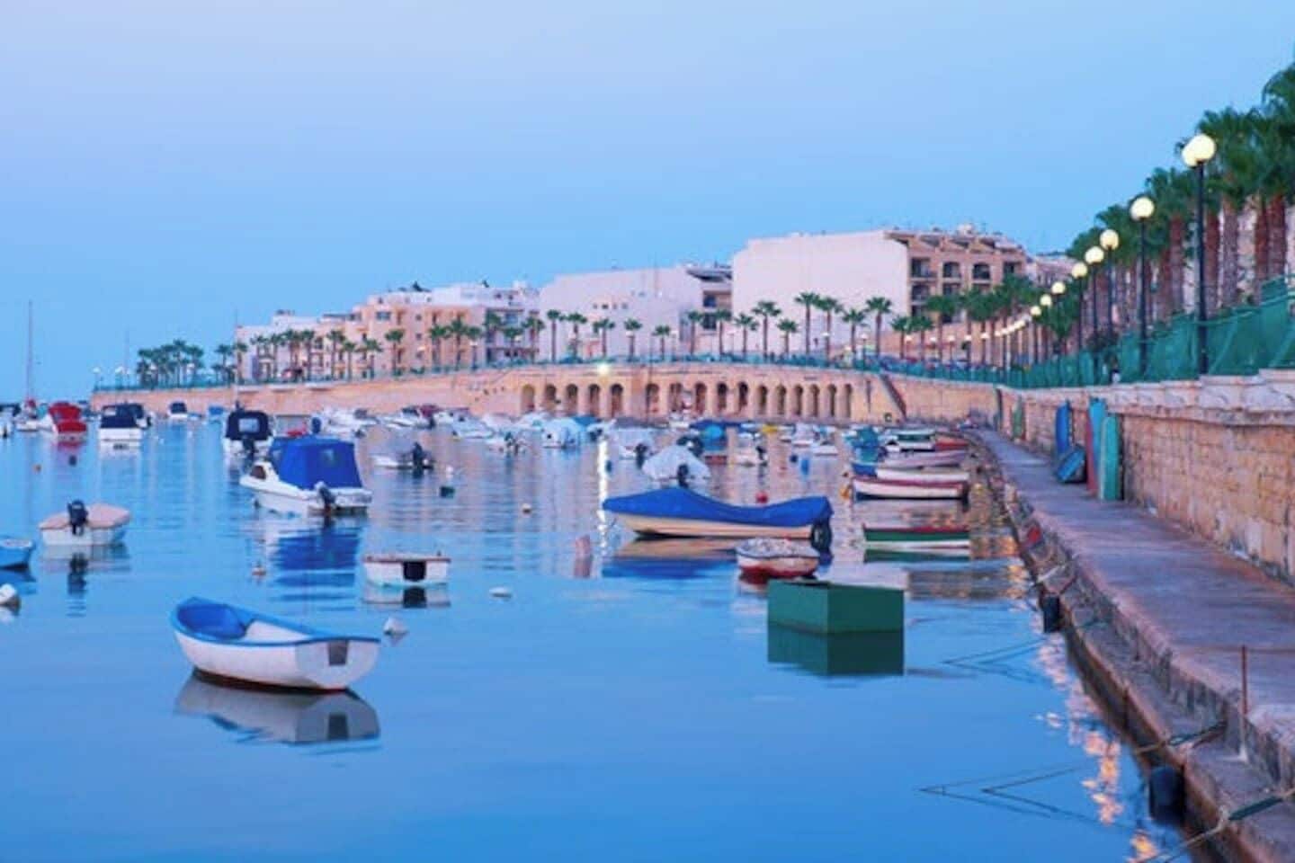 A marina with boats docked along a waterfront promenade.