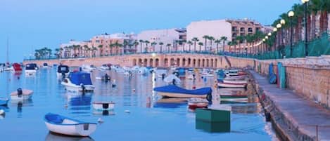 A marina with boats docked along a waterfront promenade.