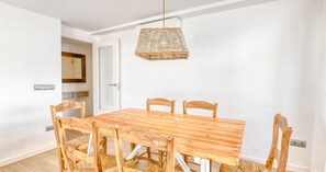 A dining area with a wooden table and chairs, a hanging light fixture, and a door leading to another room. - Ground-floor apartment with a spacious terrace in the center of Calella de Palafrugell (Calella de Palafrugell)