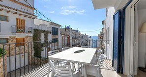 A balcony with a white table and chairs, overlooking a street with buildings and a view of the sea. - Ground-floor apartment with a spacious terrace in the center of Calella de Palafrugell (Calella de Palafrugell)