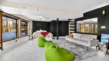 A modern living room with a large bed, a sofa, and green bean bags.