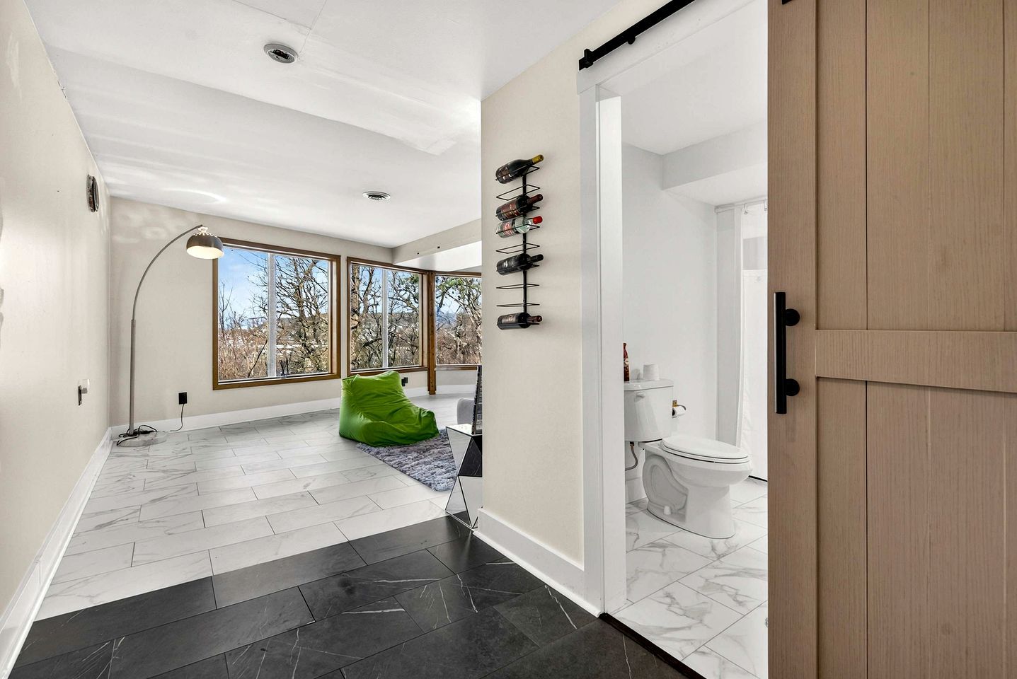 Un intérieur moderne avec un couloir menant à une salle de bain, de grandes fenêtres et un fauteuil en forme de haricot vert.