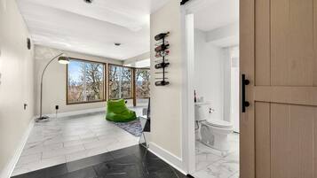 Un intérieur moderne avec un couloir menant à une salle de bain, de grandes fenêtres et un fauteuil en forme de haricot vert.