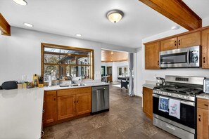 Una cocina moderna con armarios de madera, electrodomésticos de acero inoxidable y un ventanal grande.