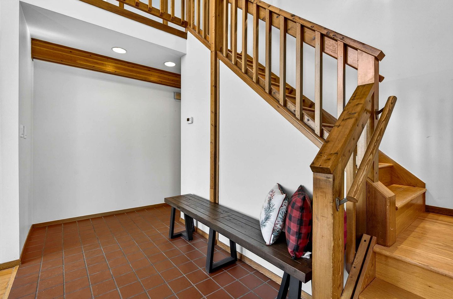Una escalera con barandillas de madera y un banco con almohadones.