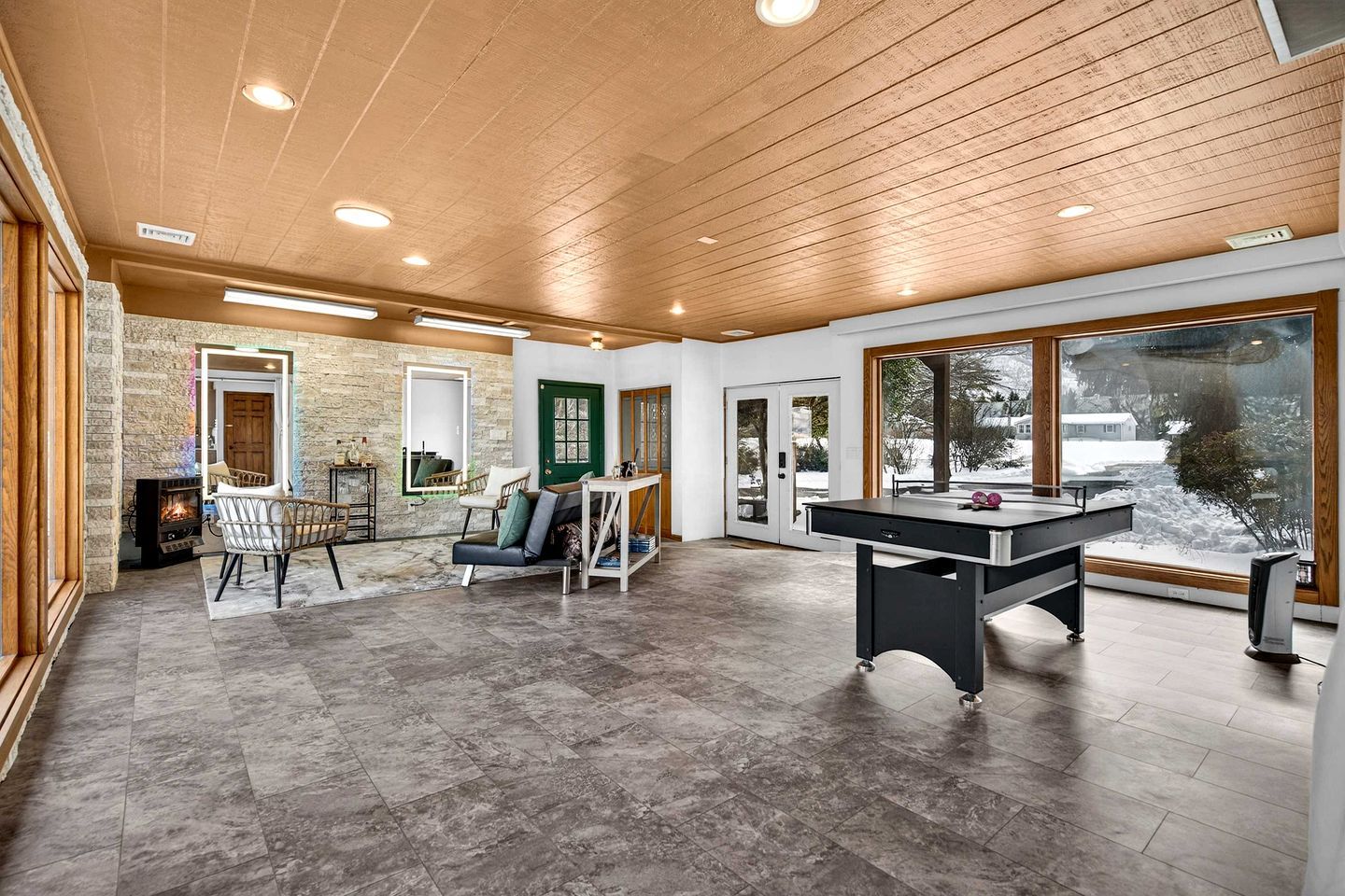 Una habitación amplia con mesa de fútbol de mesa, chimenea y un gran ventanal con vistas al exterior.