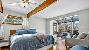 A bedroom with a large bed, a ceiling fan, a window with curtains, and a view of the outdoors. - Modern Mountain Cabin with Hot Tub and Game Room Near Moorefield, West Virginia (Moorefield)