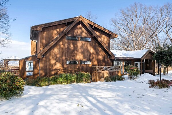 Une cabane en bois avec un toit en pente, une véranda et une allée enneigée.