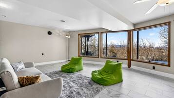 A spacious room with a large window, a ceiling fan, and a grey rug.