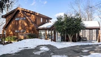 A wooden cabin with a covered porch and a snow-covered driveway.