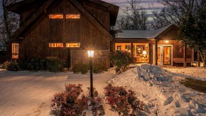 A wooden cabin with a large front entrance, a snow-covered driveway, and a well-lit exterior. - Modern Mountain Cabin with Hot Tub and Game Room Near Moorefield, West Virginia (Moorefield)
