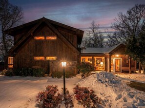 A wooden cabin with a large front entrance, a snow-covered driveway, and a well-lit exterior. - Modern Mountain Cabin with Hot Tub and Game Room Near Moorefield, West Virginia (Moorefield)