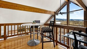 A room with a wooden ceiling, a round table, two chairs, and a view of a snowy landscape through large windows. - Modern Mountain Cabin with Hot Tub and Game Room Near Moorefield, West Virginia (Moorefield)