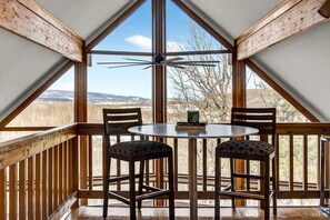 Una habitación con techo de madera y un ventanal con vistas a un paisaje montañoso.
