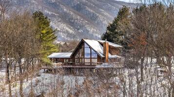 A cabin with a wooden exterior, large windows, and a deck.