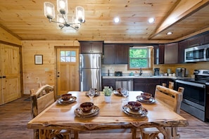 Interior de madera con una mesa de comedor para cuatro, electrodomésticos de cocina y una ventana.