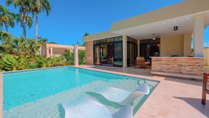 Ein moderner Poolbereich mit klarem Wasser, Liegestühlen und einer Terrasse mit Sitzgelegenheiten.