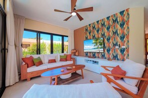 A modern living room with a sofa, coffee table, and armchair, a ceiling fan, and a TV on the wall. - 2 Bed, Encuentro Retreat, Casa Tranquila (sosua)