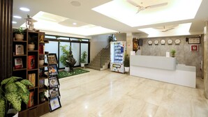 Eine Hotelhalle mit Rezeption, einer Treppe und einem Verkaufsautomaten.