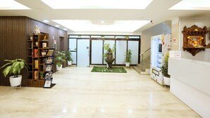 Eine großzügige Lobby mit einer Rezeption, einer Buddha-Statue und einem Verkaufsautomaten.