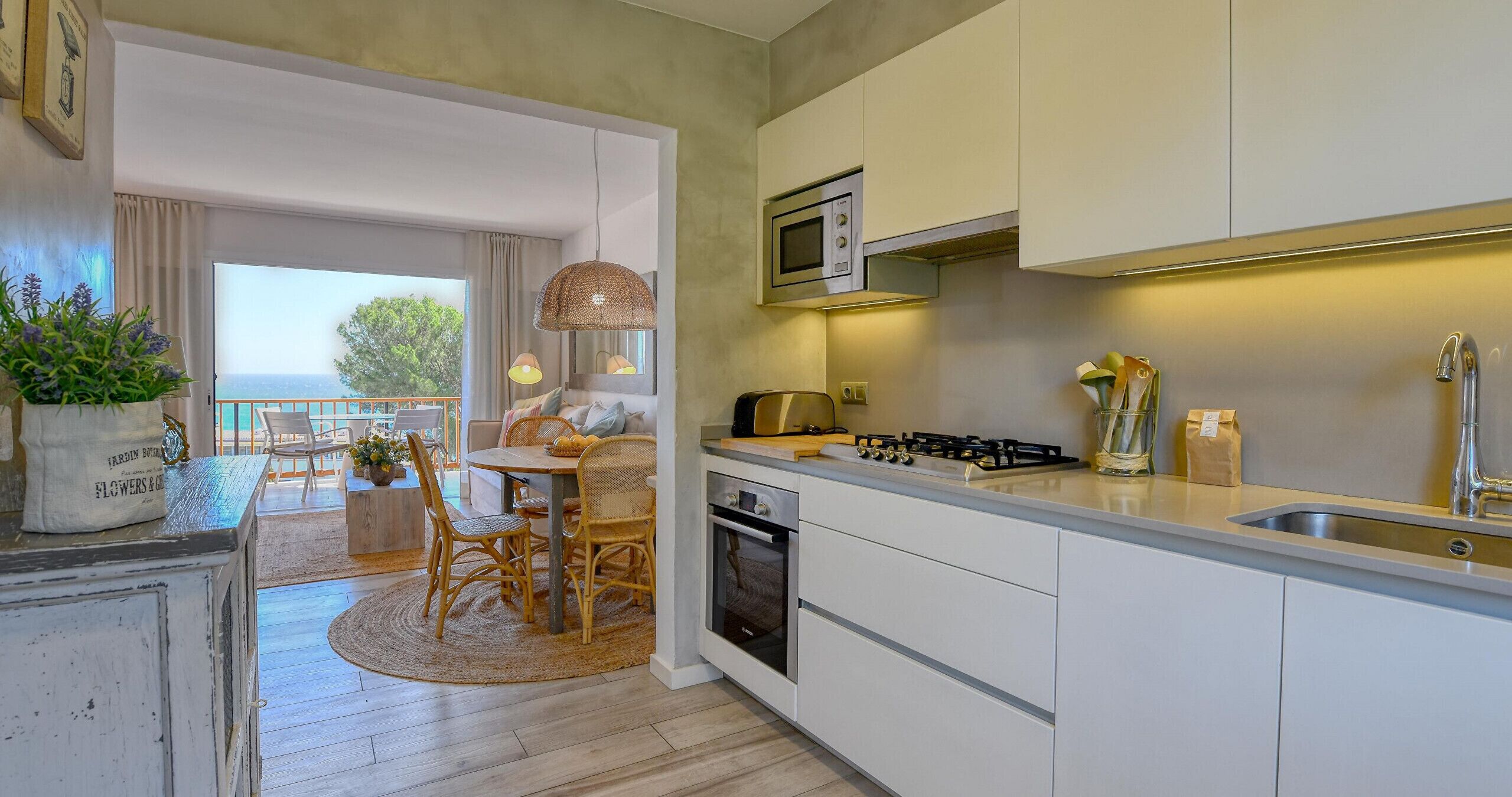 Une cuisine moderne avec des meubles blancs, une cuisinière à gaz et un four à micro-ondes.