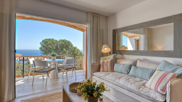 Ein Balkon mit Tisch und Stühlen, eine Couch mit Kissen und ein großer Spiegel an der Wand.
