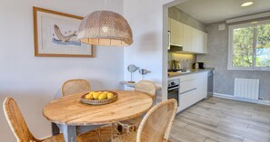 A dining area with a round wooden table, wicker chairs, and a basket of lemons.