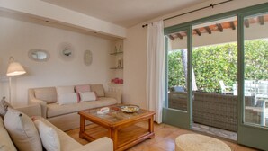 Un salón con sofá, una mesa de centro y vistas al exterior a través de un ventanal.