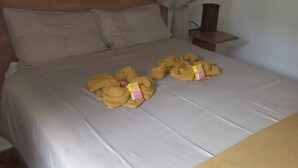 Een bed met een wit laken, twee gele handdoeken en een klein doosje op het bed.
