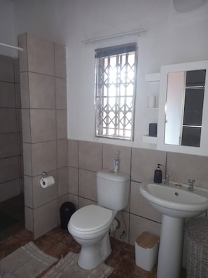 Casa de banho com sanita, lavatório, janela e paredes em azulejo.