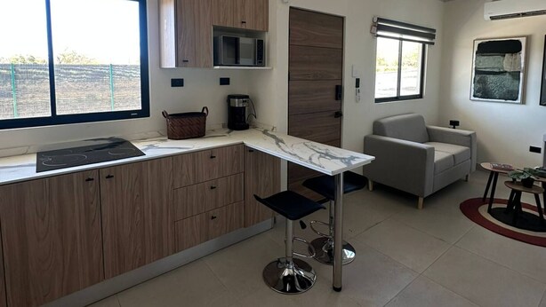 A modern kitchen with wooden cabinets, a microwave, and a large window. - Tempátika Villa 3, New (Tempate)