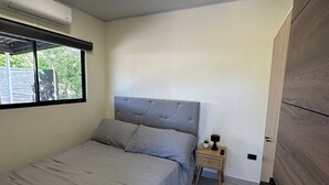 A bedroom with a bed, a nightstand, a window, and a door. - Tempátika Villa 3, New (Tempate)