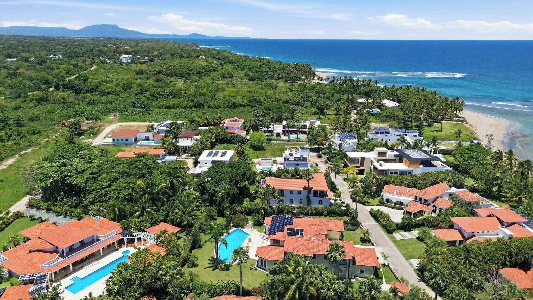 A coastal residential area with houses, a beach, and a clear view of the ocean.