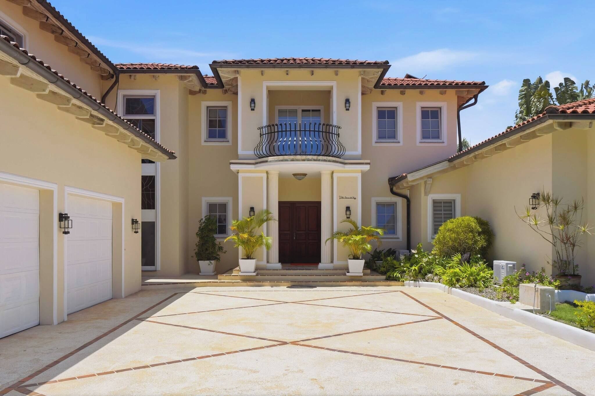 A two-story house with a central entrance, a balcony, and a driveway leading to a garage.