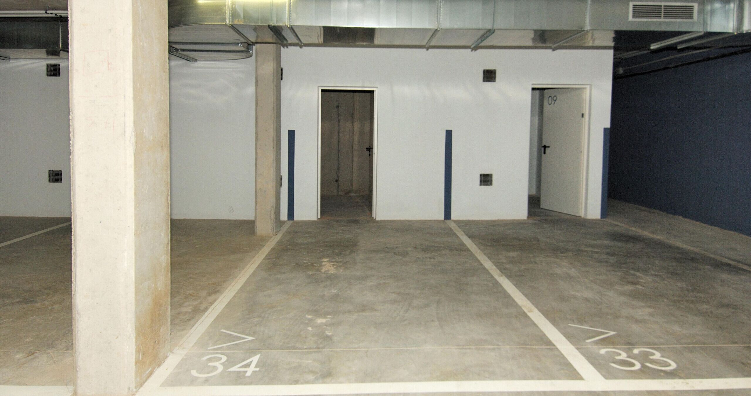 Un corridoio con porte numerate 34 e 33, che conduce a una stanza con una parete blu.