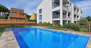 A rectangular swimming pool with clear blue water, surrounded by a wooden deck. - Modern three-bedroom apartment with pool in the center (Calella de Palafrugell)