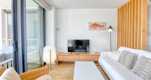 A modern living room with a sofa, a coffee table, a TV, and a lamp. - Modern three-bedroom apartment with pool in the center (Calella de Palafrugell)
