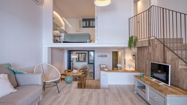 Een modern appartement met een eethoek, een bank, een televisie en een trap.