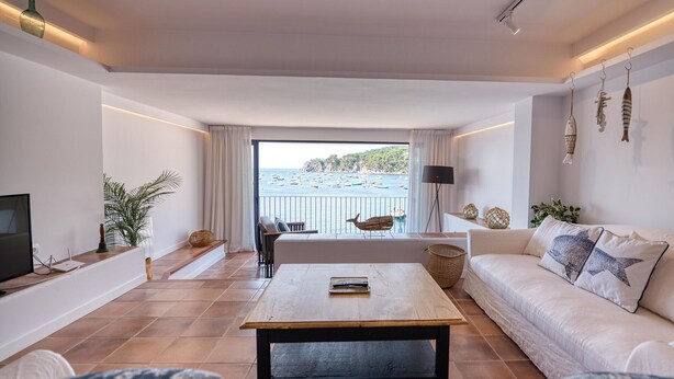 Una sala de estar con vistas al mar, un sofá, una mesa de centro y un televisor.