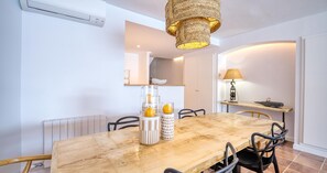 Ein Essbereich mit Holztisch, Stühlen, einer Hängelampe und einem Spiegel an der Wand.