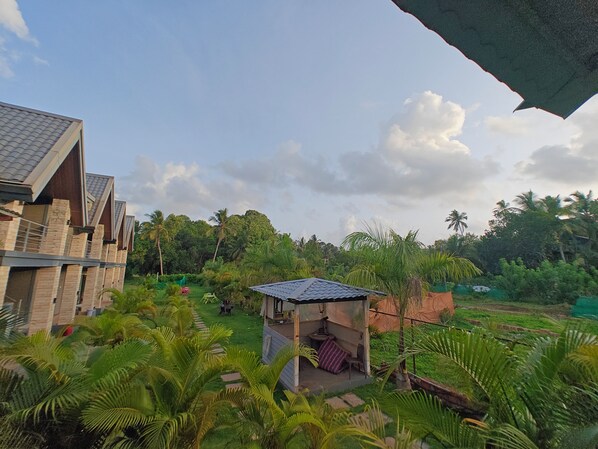 A modern building with a unique architectural design, surrounded by lush greenery and palm trees. - Mermaid Avisa (Arambol)