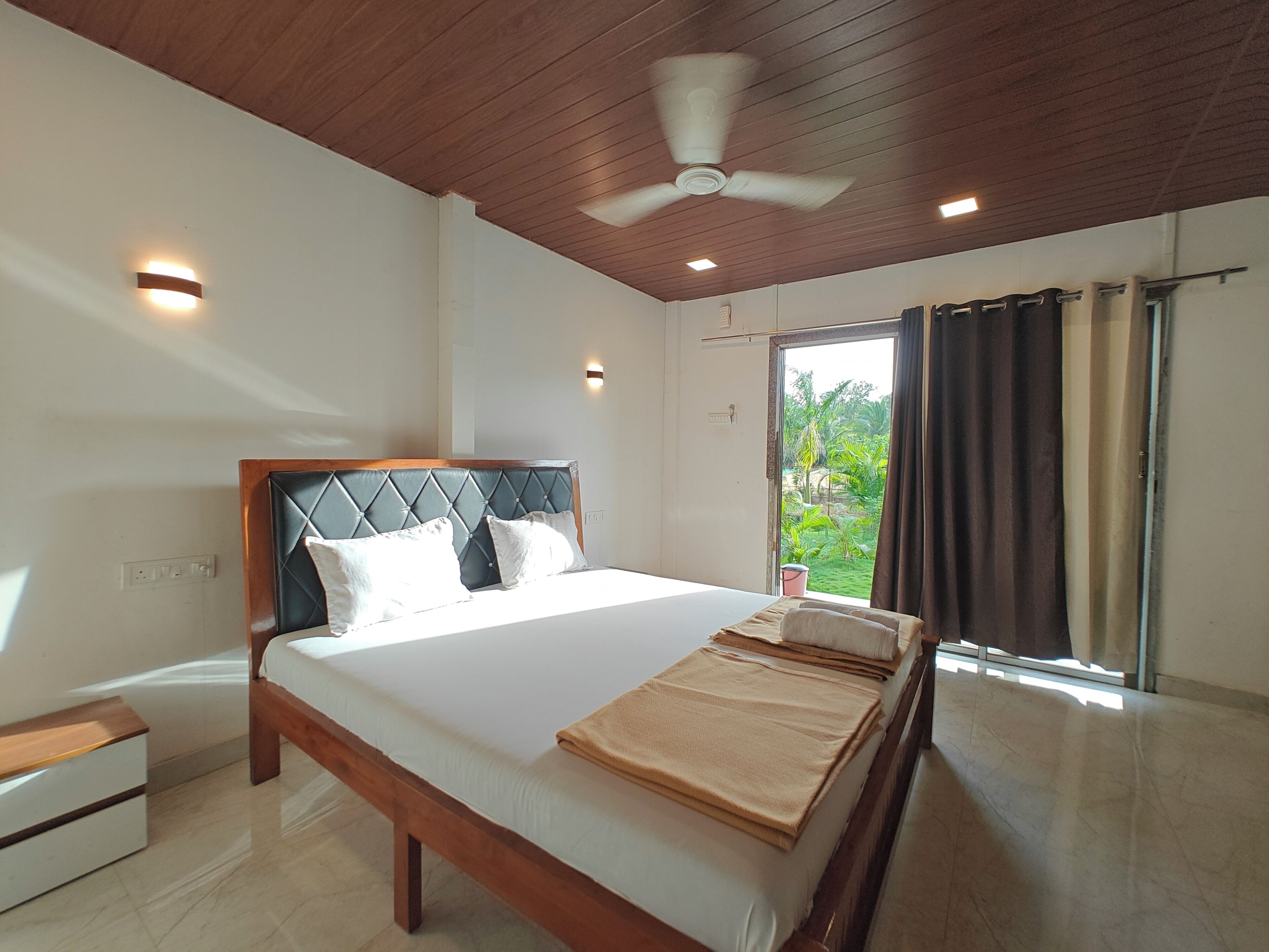 Quarto com uma cama grande, um ventilador de teto e vista para o exterior pela janela.