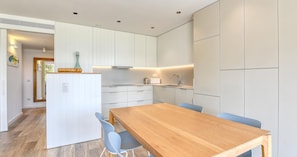 Eine moderne Küche mit weißen Schränken, einem Holzespeisetisch und blauen Stühlen.