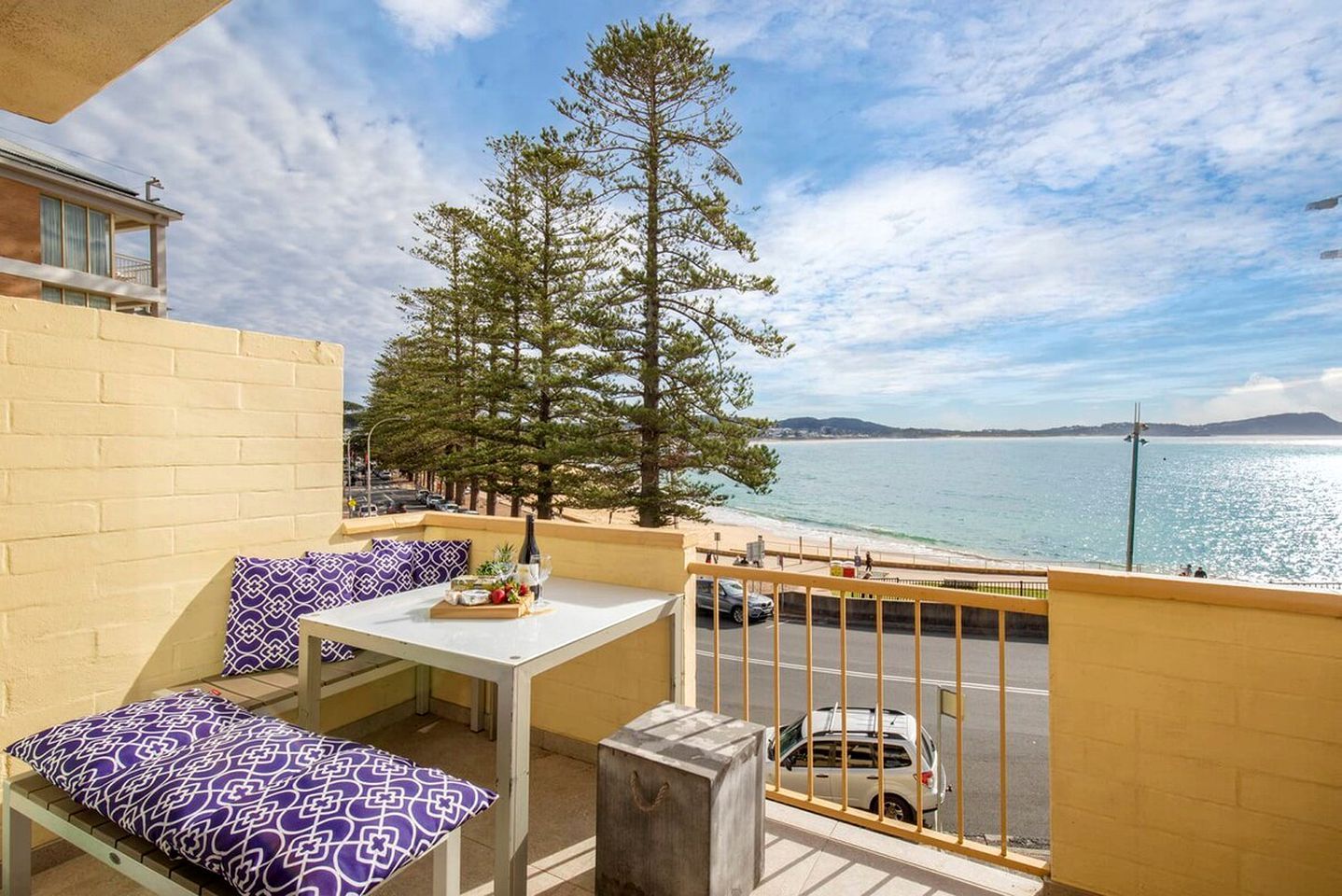 A balcony with a table, chairs, and a view of the sea.