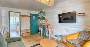 A modern living room with a flat-screen TV, a sofa, a coffee table, and a dining area with chairs and a table. - Apartment with pool, AC and tennis · Calella (Calella de Palafrugell)
