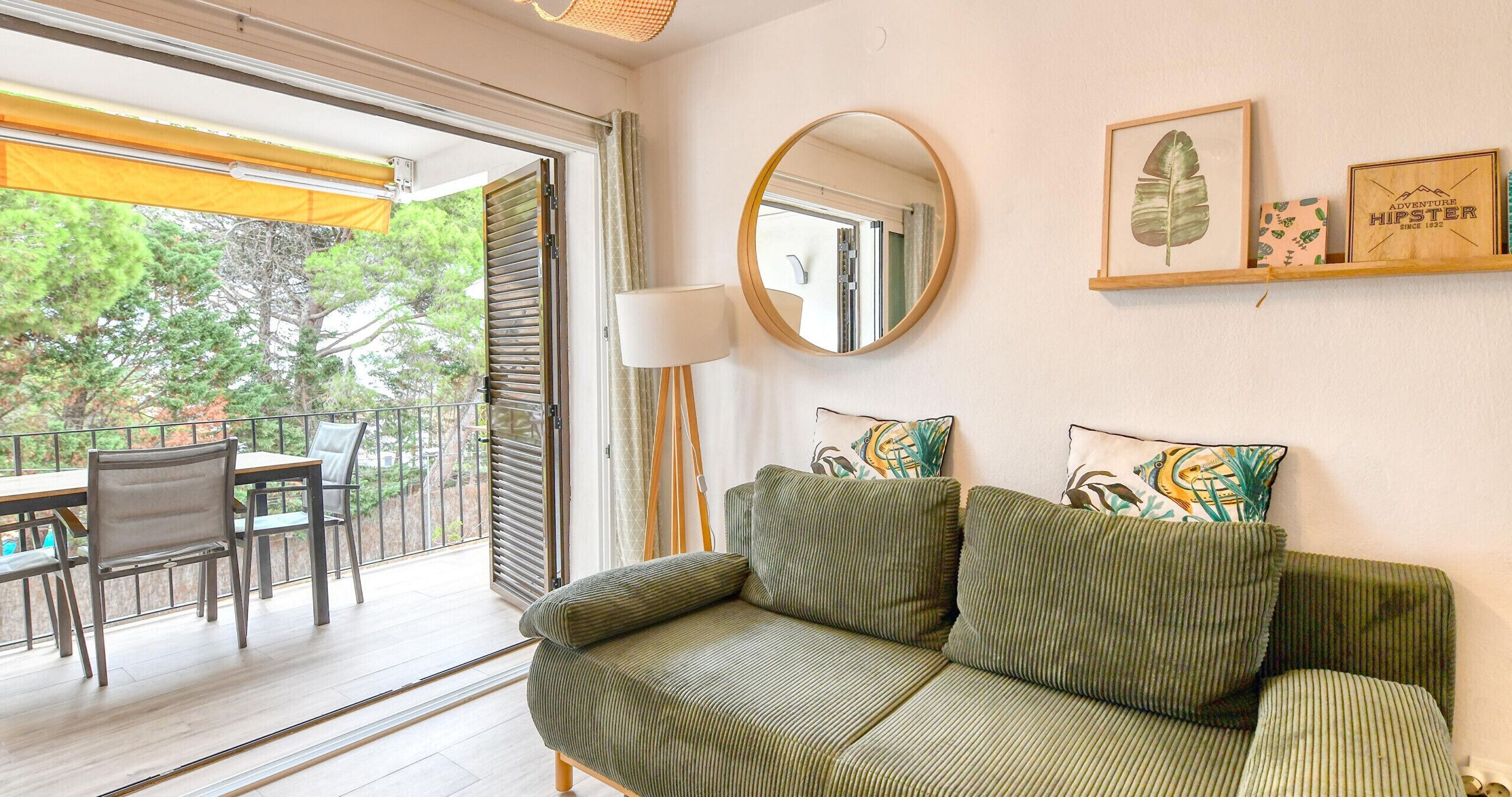 A living room with a sofa, a round mirror, and a framed picture on the wall.